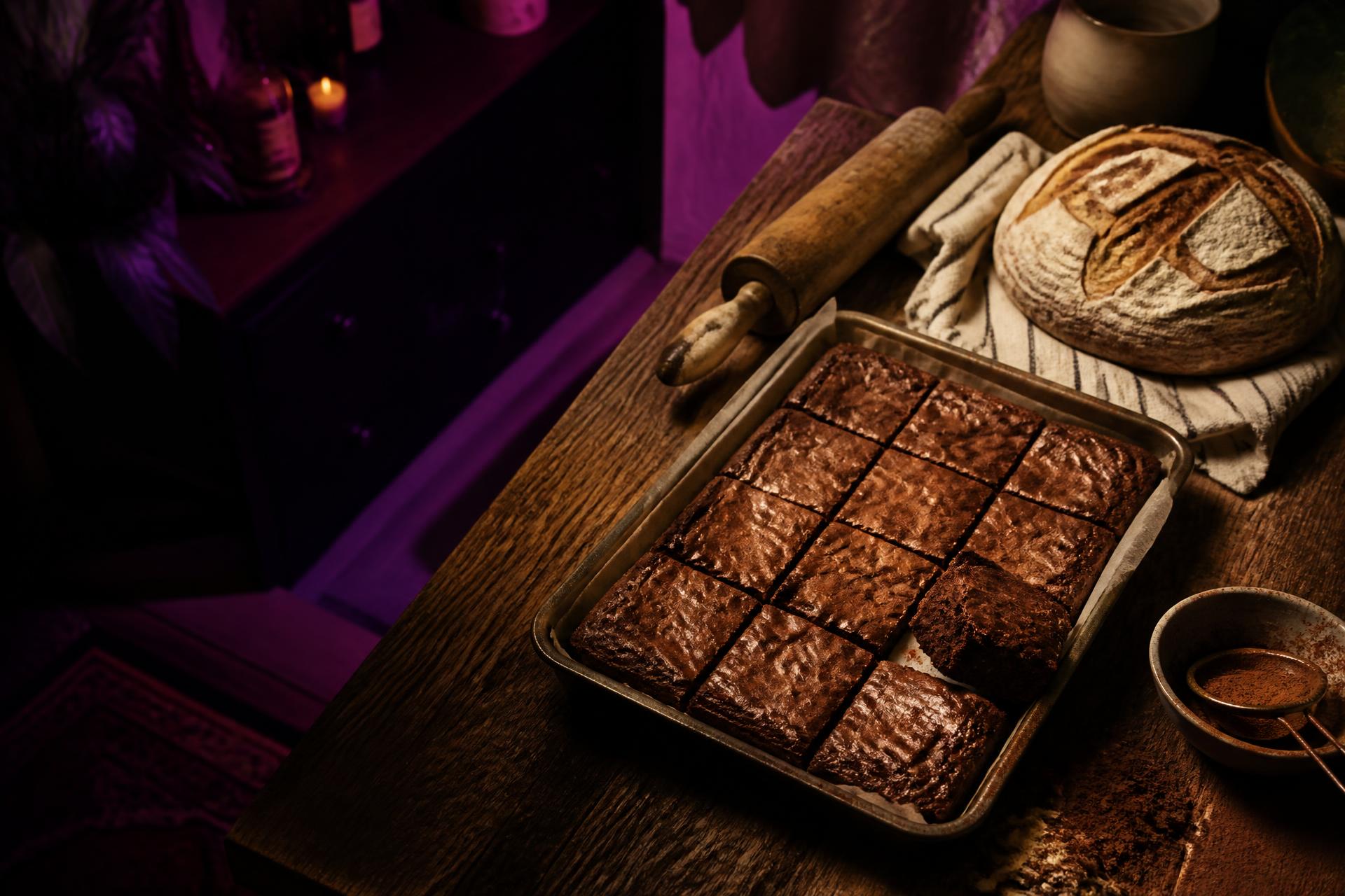 Freshly cut from-scratch brownies and a sourdough loaf on a wooden kitchen counter